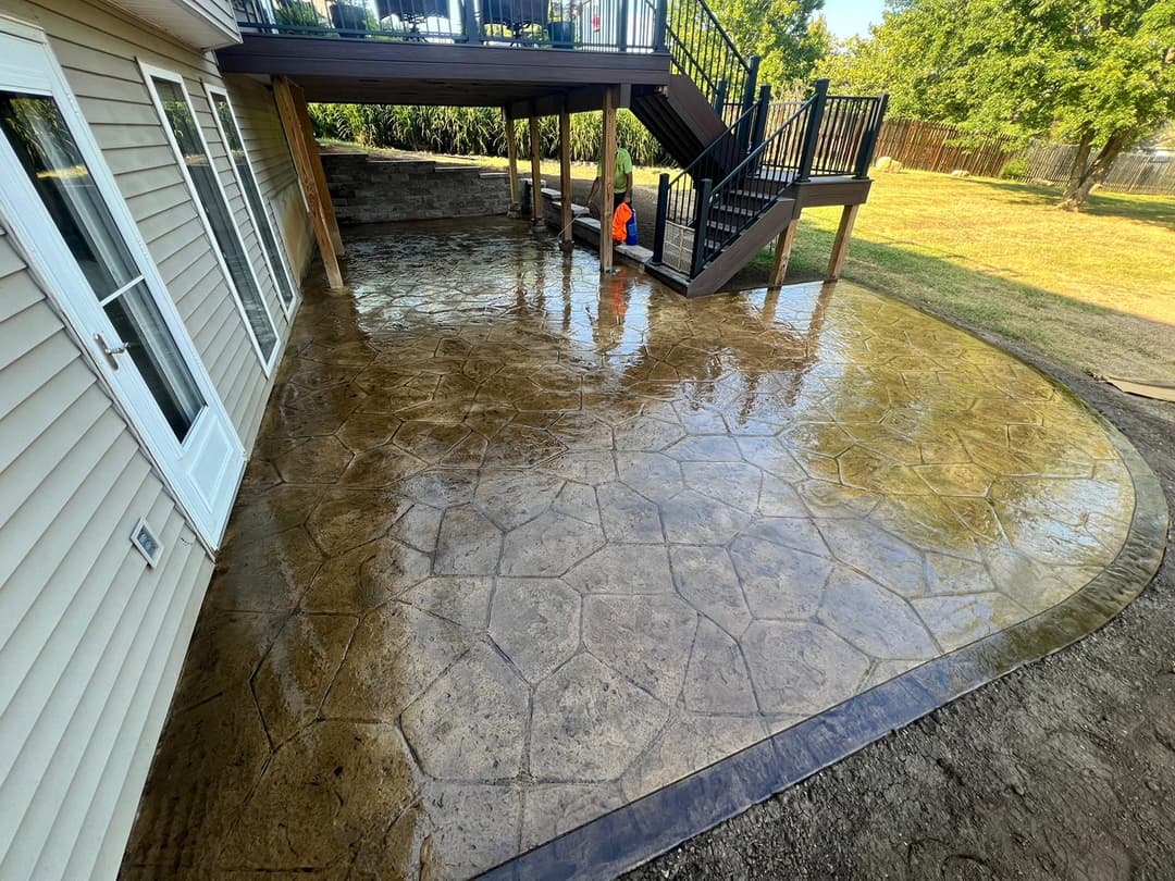 Textured stamped concrete patio beneath a deck, featuring a well-maintained outdoor space.