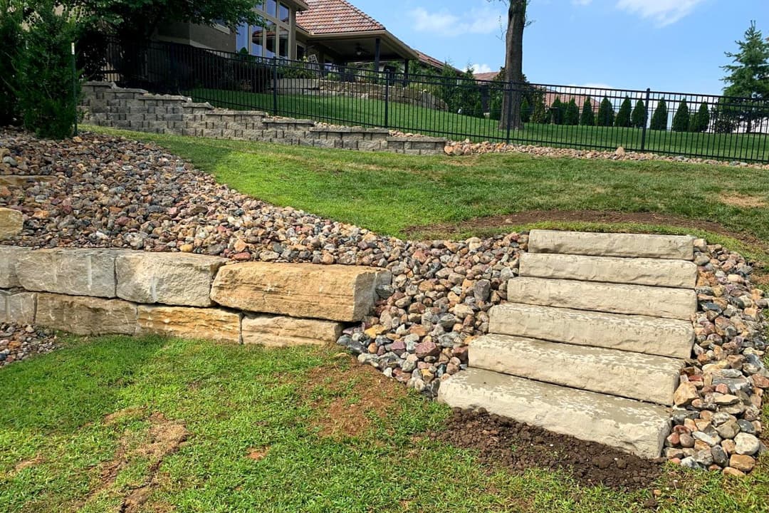 Natural stone steps leading to a landscaped garden with gravel and lush green grass.