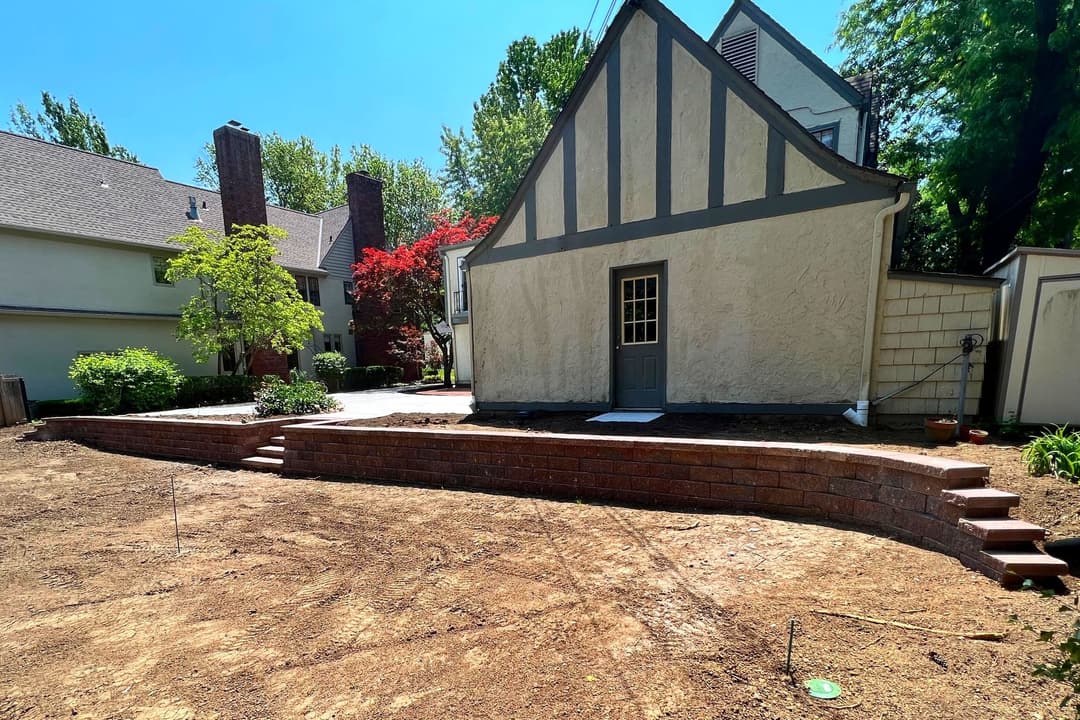 Home exterior with stone patio and tiered landscaping under a clear blue sky.