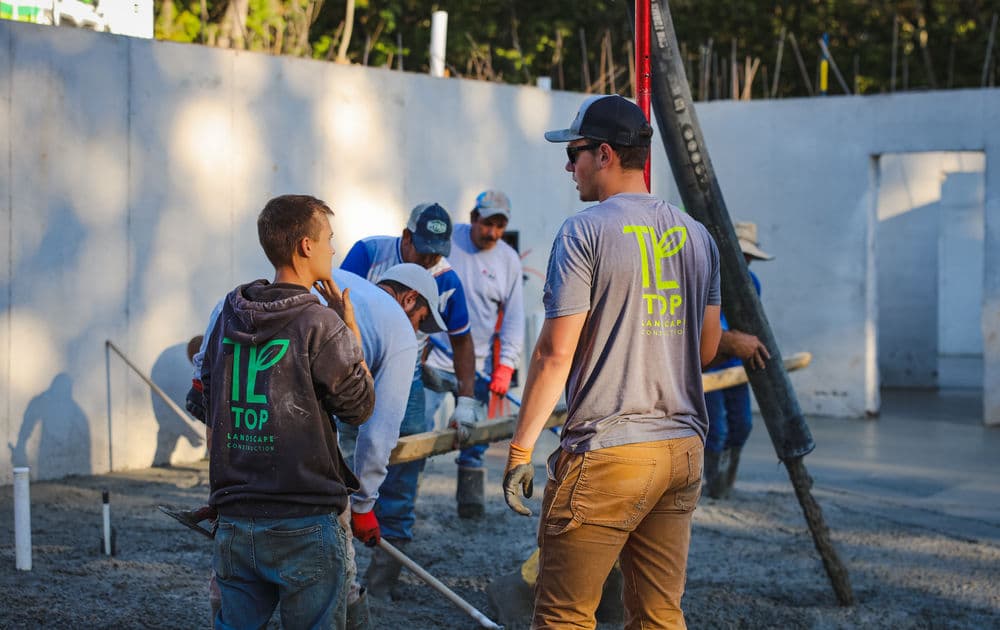Construction workers pouring concrete for a foundation at a building site.